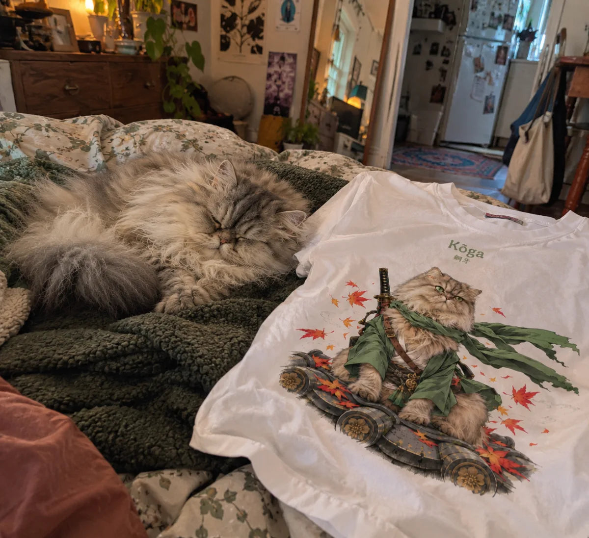 Kōga, chat persan, endormi sur le lit à côté de son t-shirt où il apparaît en samouraï au kimono vert